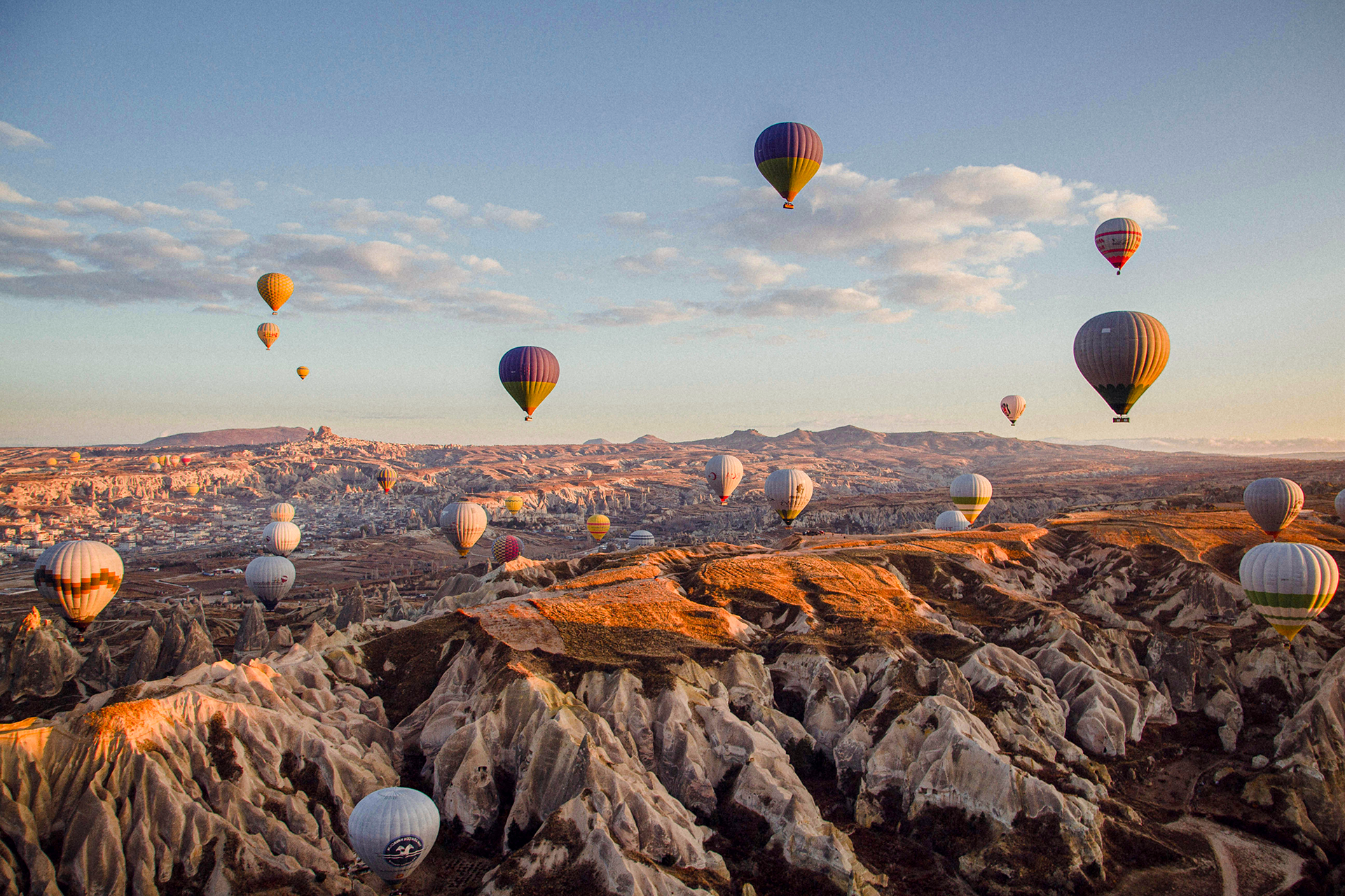 Heißluftballons über einer felsigen Landschaft bei Sonnenaufgang