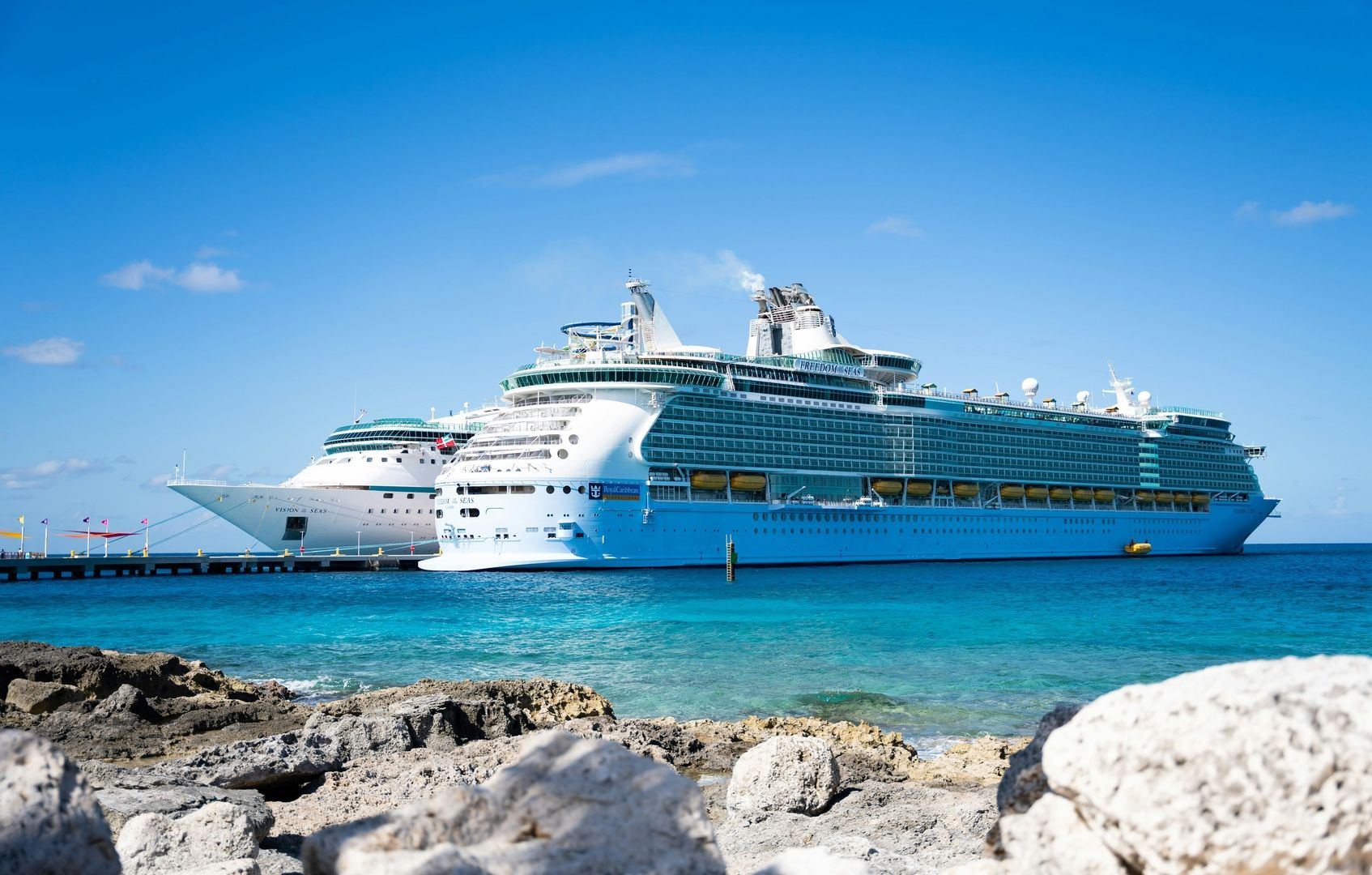Kreuzfahrtschiff vor einer tropischen Küste mit blauem Meer