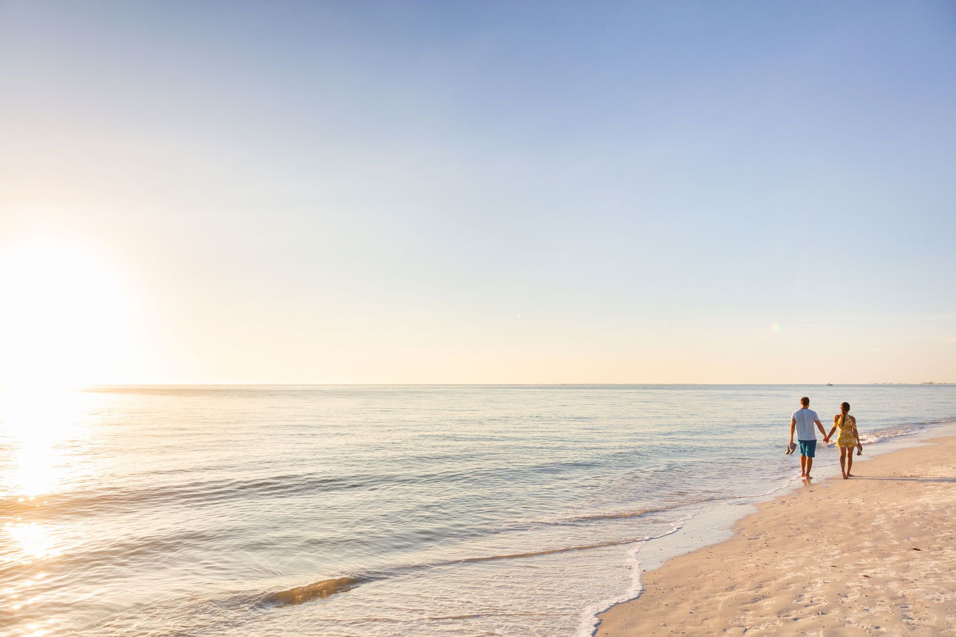 Zwei Personen gehen am Strand entlang bei Sonnenuntergang oder Sonnenaufgang